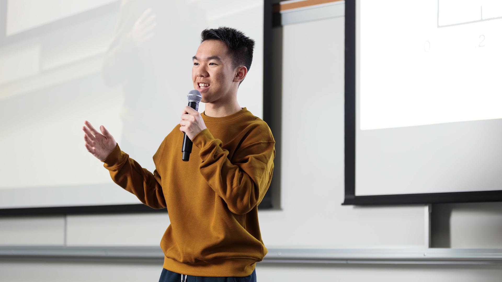 A professor stands in front of a board while teaching