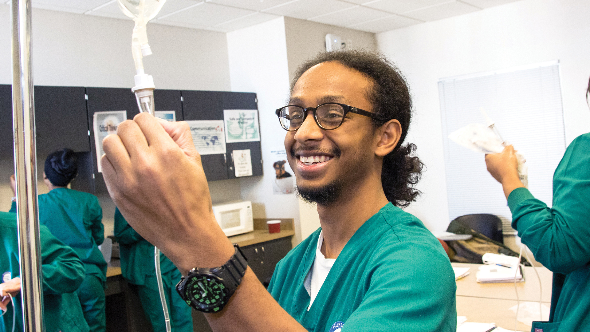 Young medical student adjusting an IV drip during a clinical skills lab
