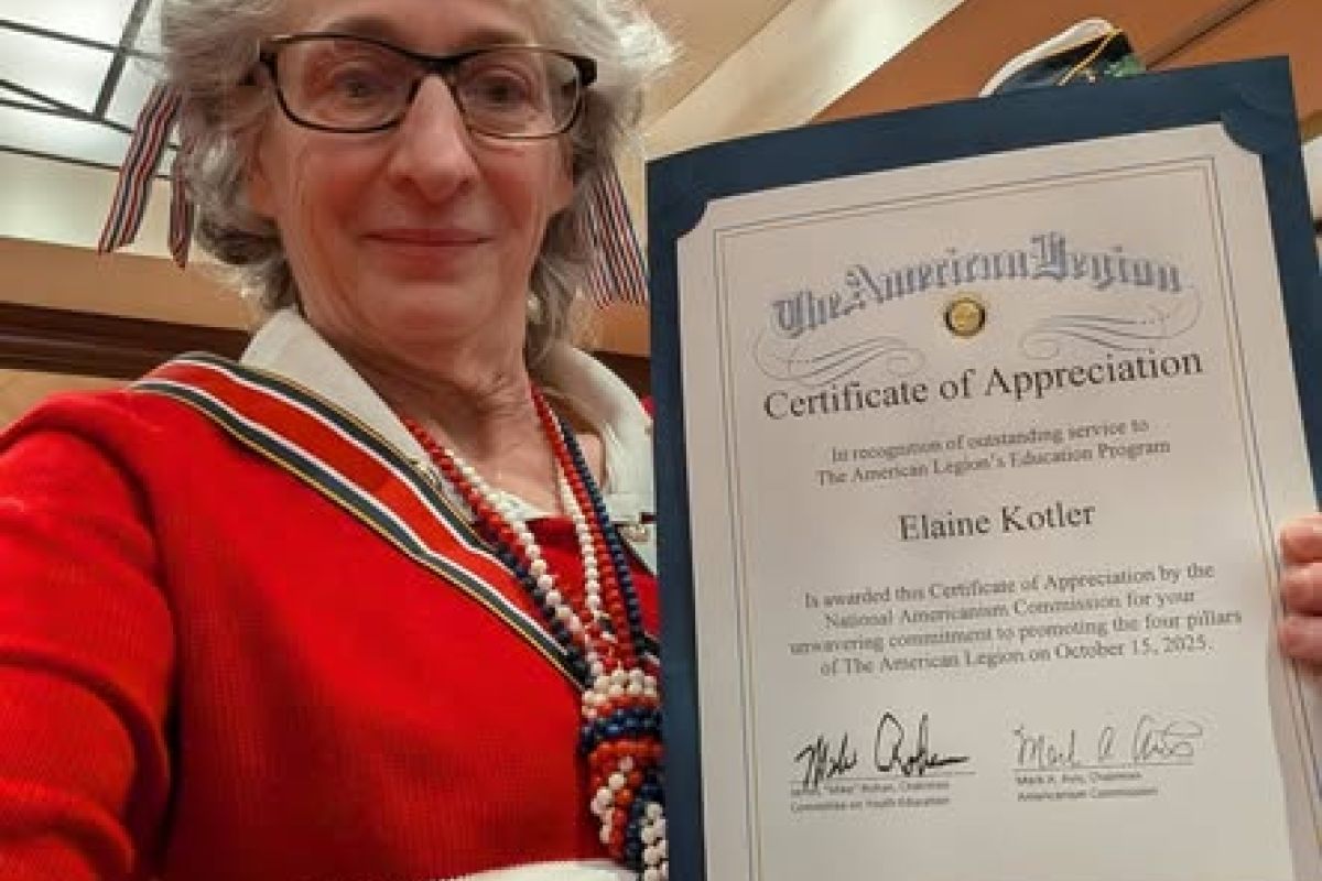 Woman in red smiles and holds certificate