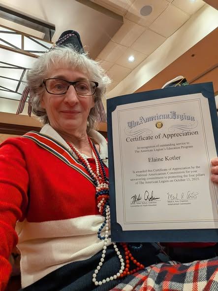 Woman in red smiles and holds certificate