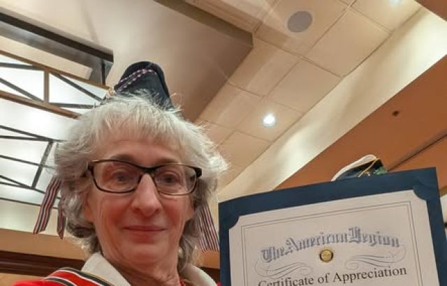 Woman in red smiles and holds certificate