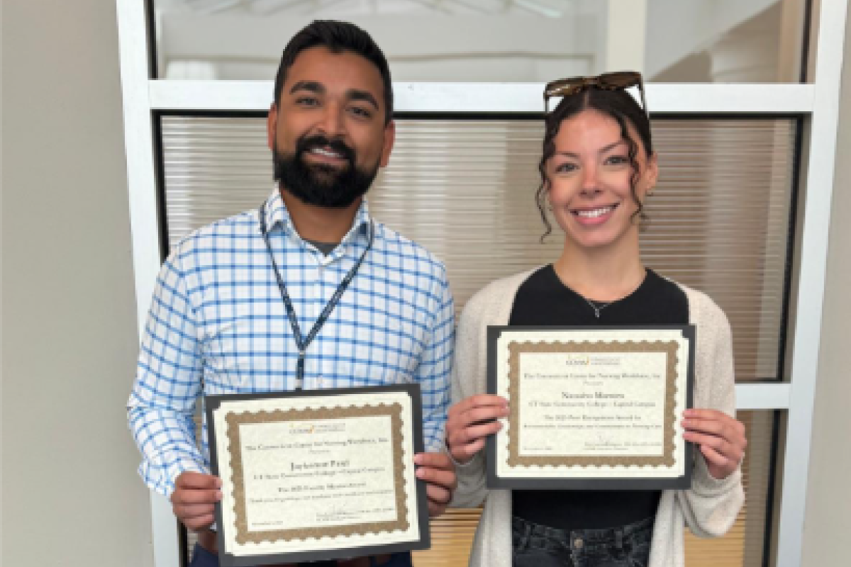 Man and woman smile into camera holding certificates
