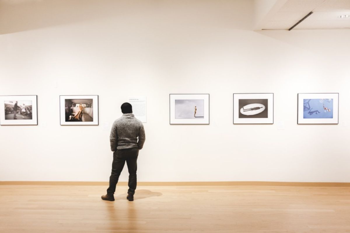 Man stands in front of a line of photographs lining the wall