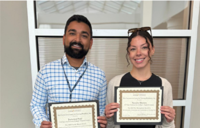 Man and woman smile into camera holding certificates