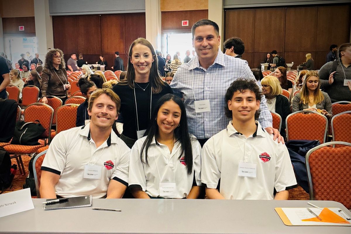 4 students sit at a table with a male professor