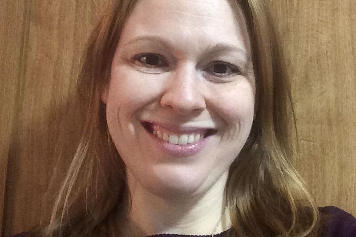woman smiling in front of wood wall