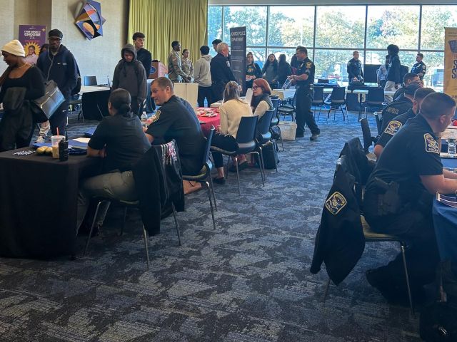 A photo of an event with people browsing different tables of vendors