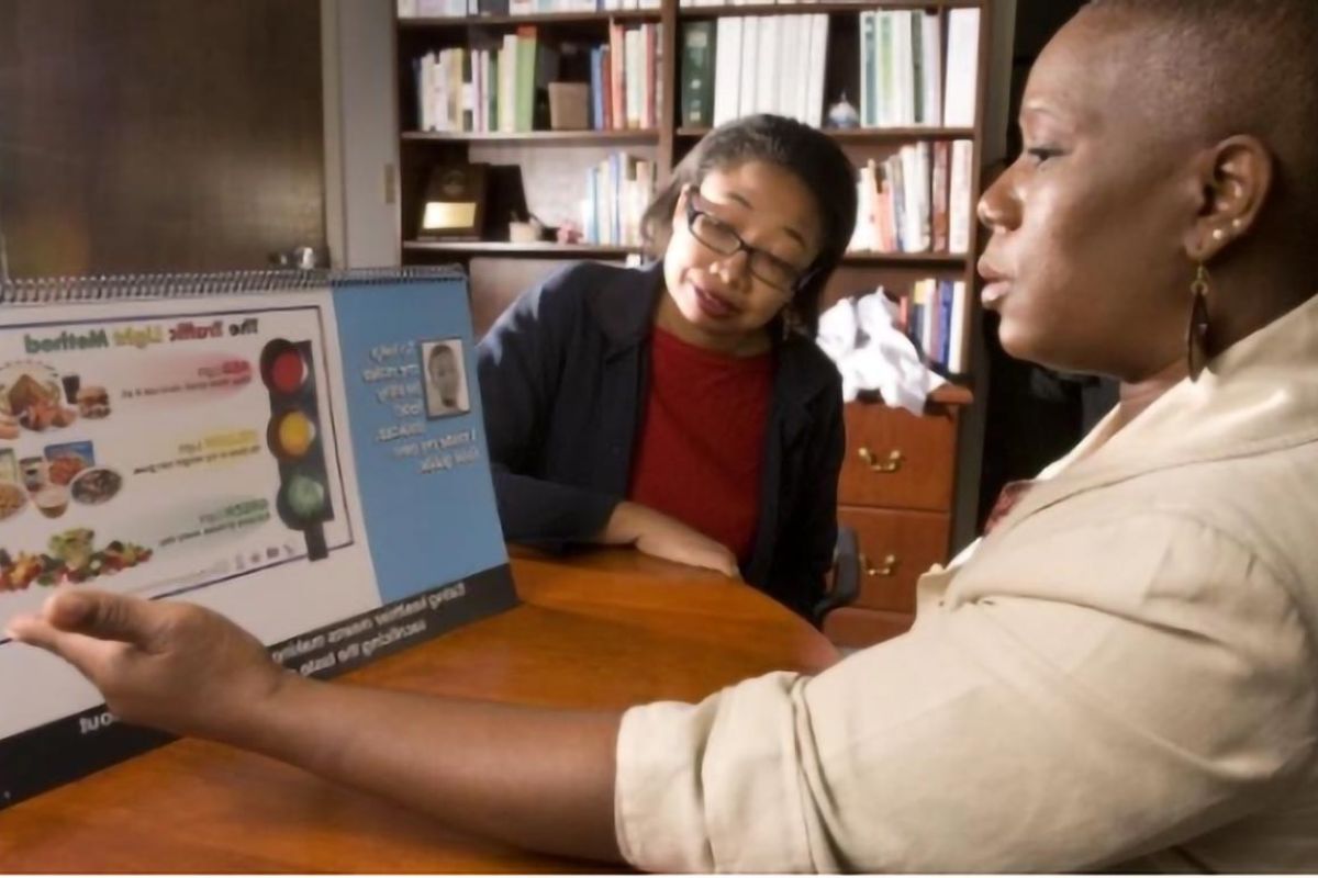 Community public health educator uses a nutrition education display to teach a participant about healthy food choices.