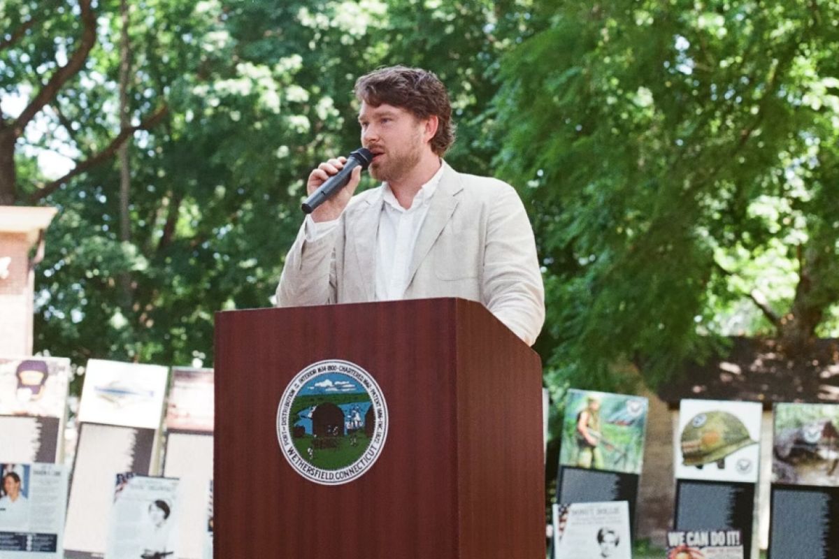 man talking into microphone on podium