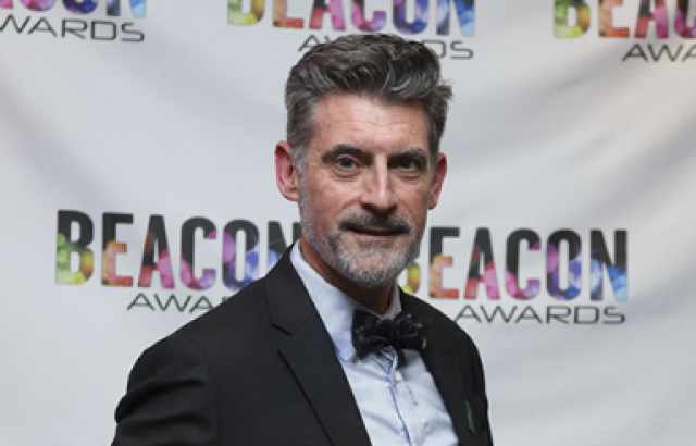 man smailes holding award