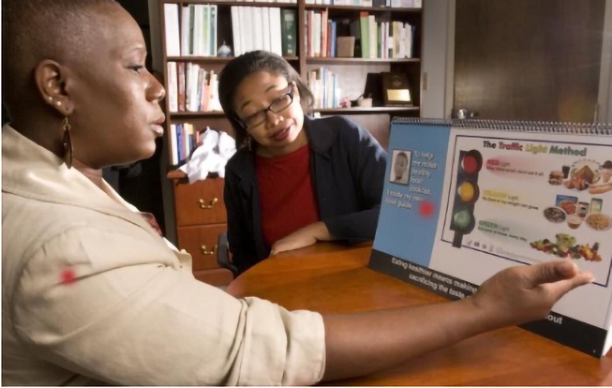 Community public health educator uses a nutrition education display to teach a participant about healthy food choices.