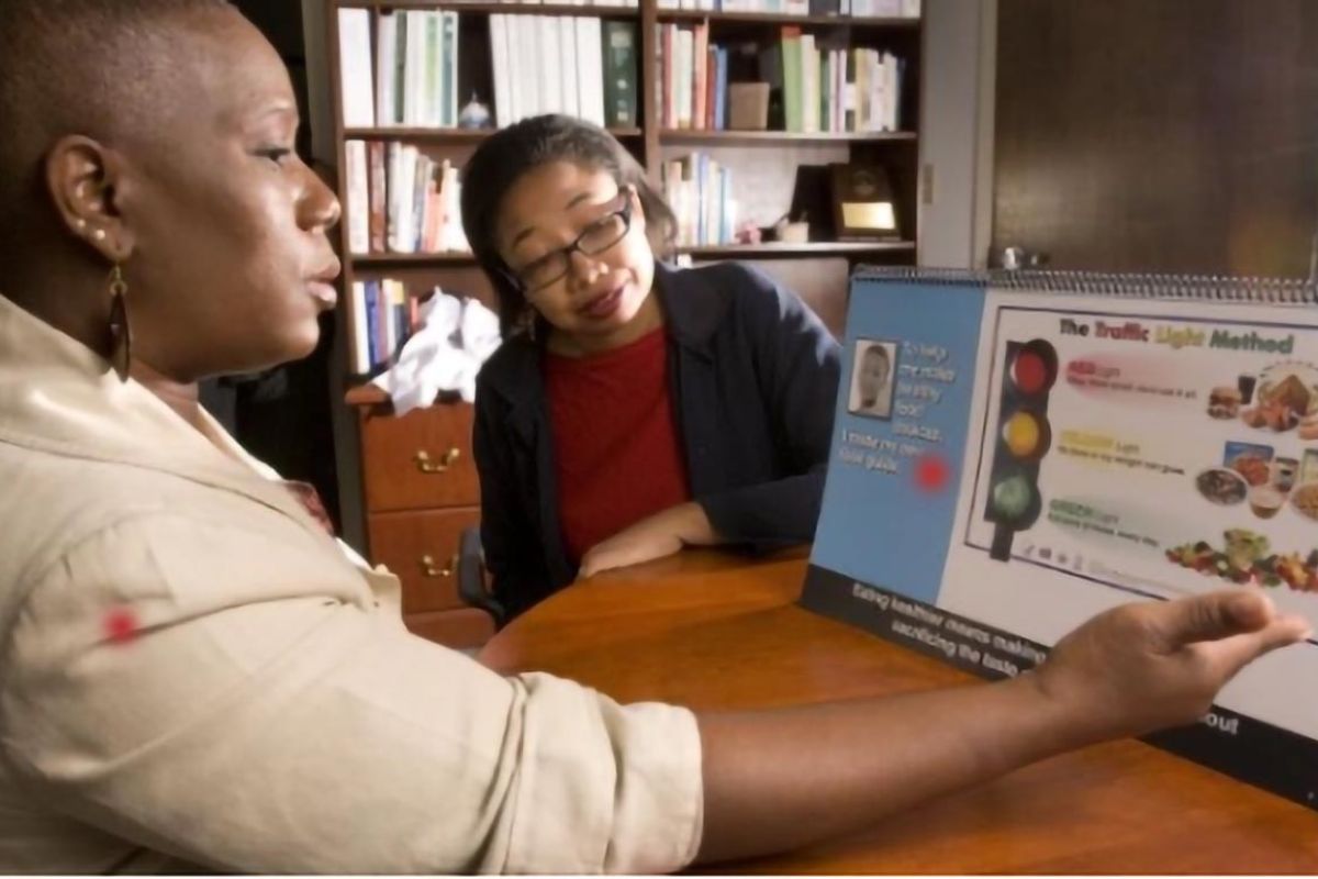 Community public health educator uses a nutrition education display to teach a participant about healthy food choices.