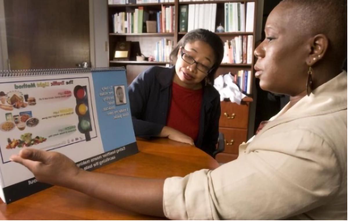 Community public health educator uses a nutrition education display to teach a participant about healthy food choices.