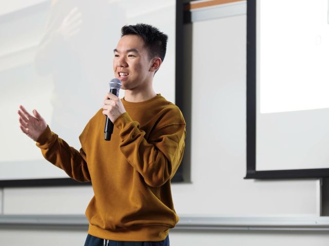 A professor stands in front of a board while teaching