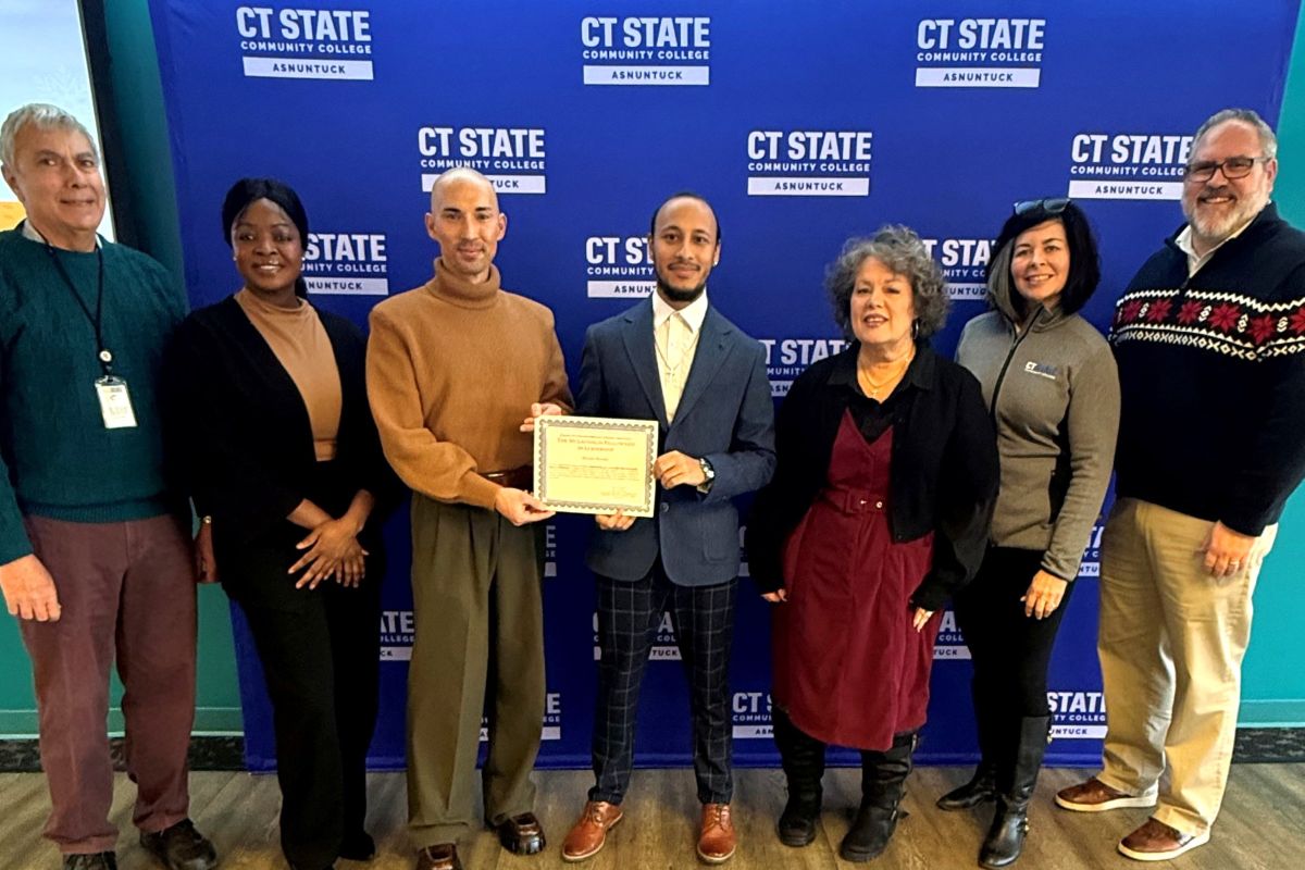 Group of people stand with young man holding certificate