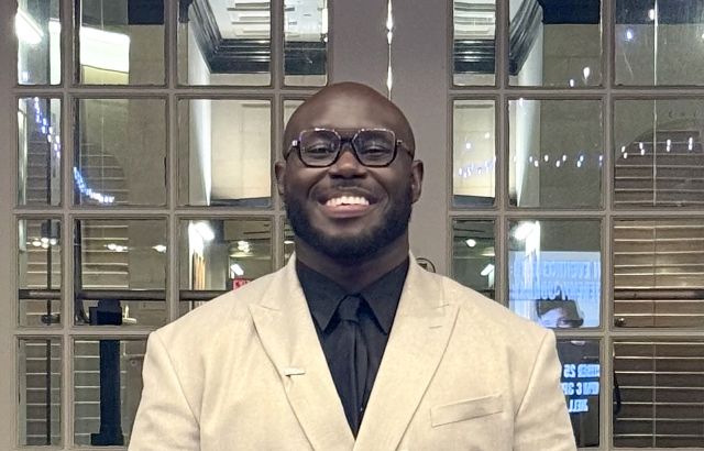 Jordan Long smiles into the camera in a white shuit jacket.