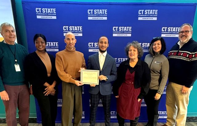 Group of people stand with young man holding certificate