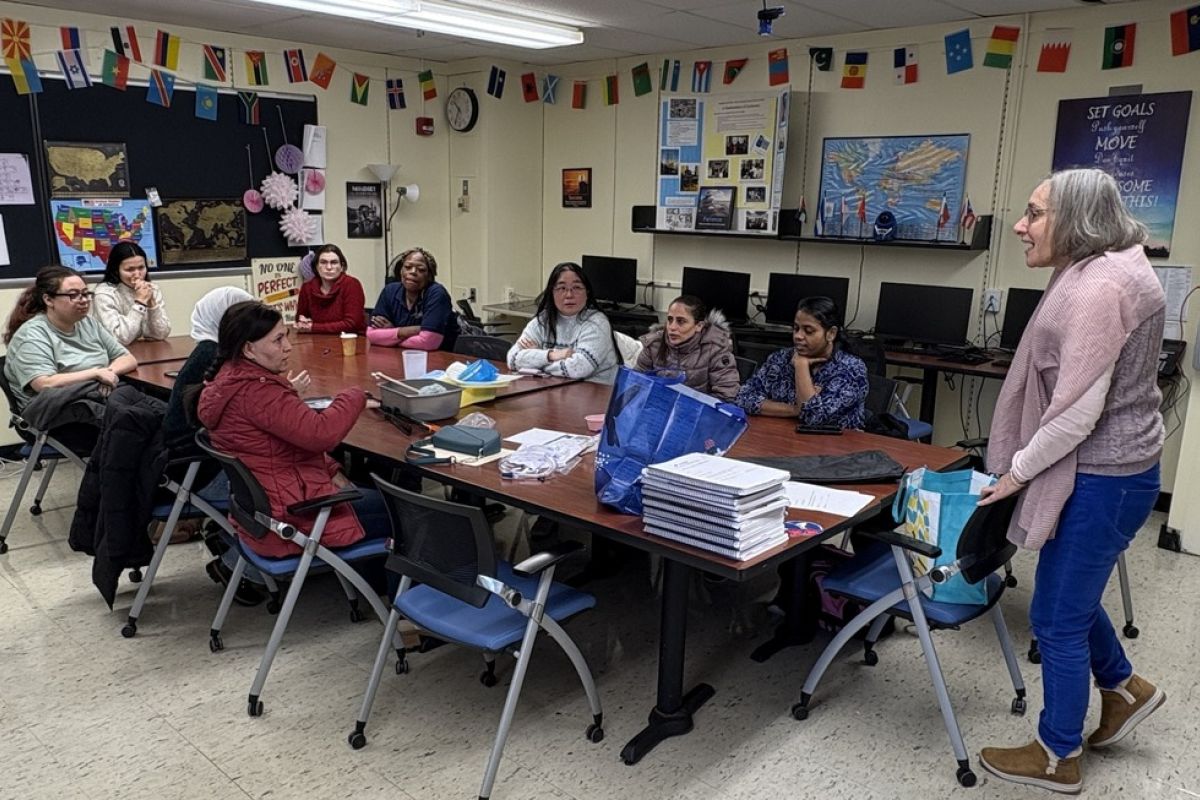CNA students sitting around a conference-table in a classroom at Vernon, CT — a group of adult-education students enrolled in the CNA program listening to an instructor.