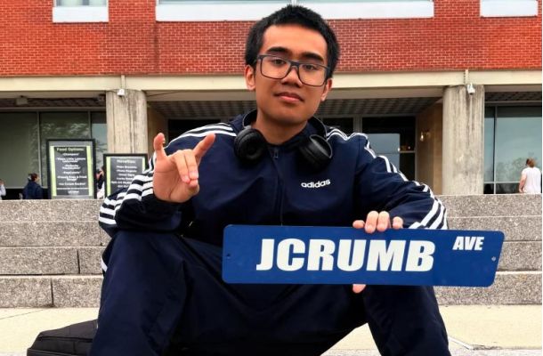 Jacob Crumb holds a street sign that says JCrumb Ave.