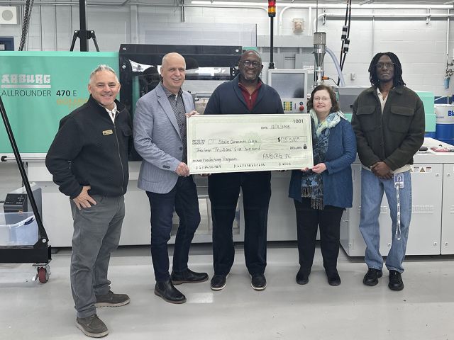 Five people hold a replica of a $13,500 check