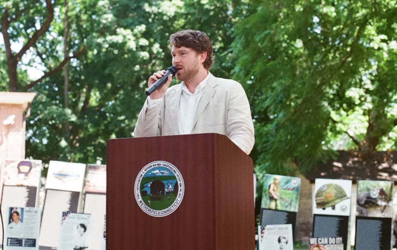 man talking into microphone on podium