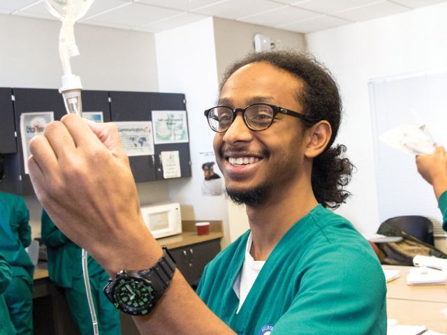 Young medical student adjusting an IV drip during a clinical skills lab