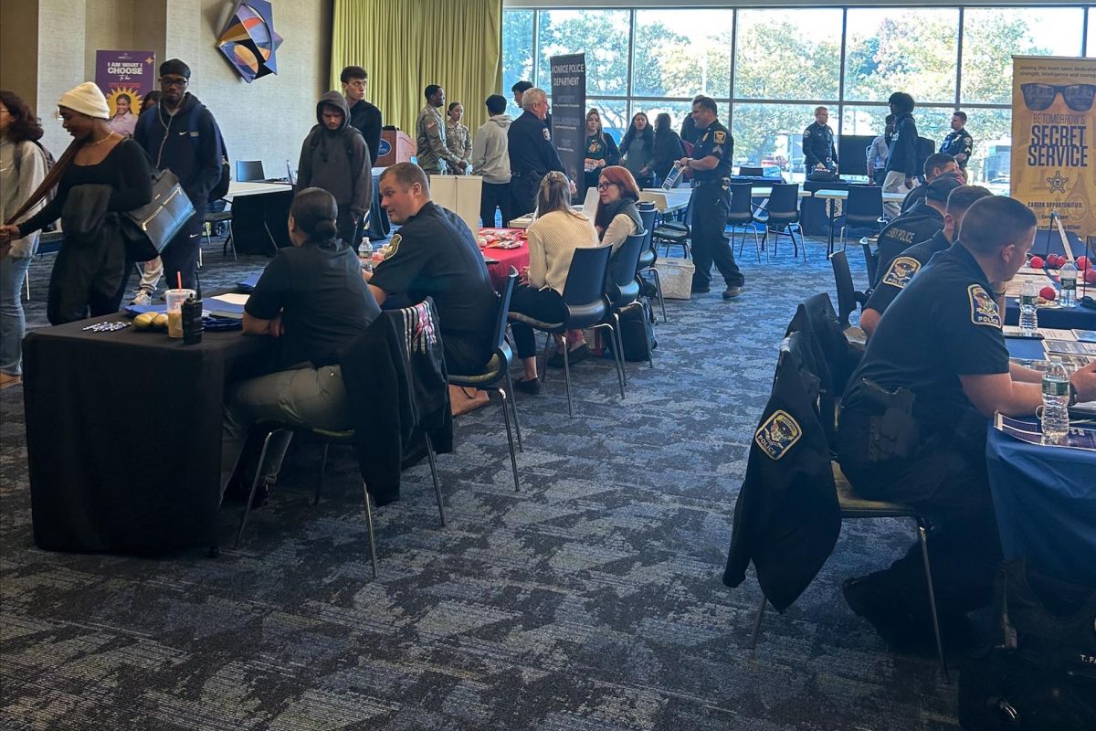 A photo of an event with people browsing different tables of vendors