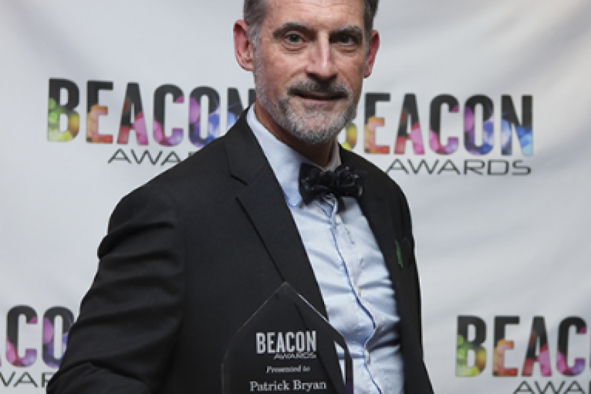 man smailes holding award